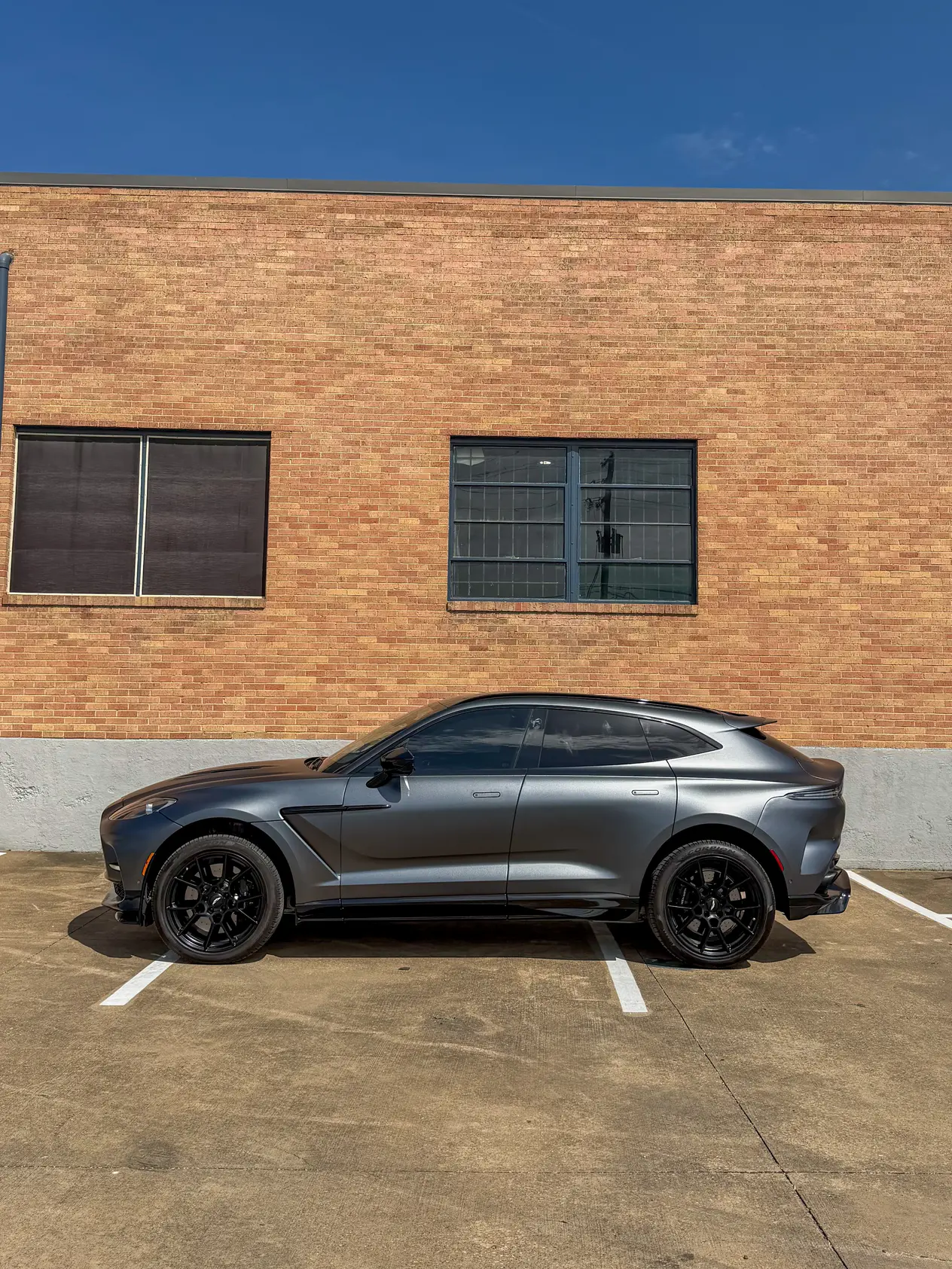 Gray 2024 Aston Martin DBX707 parked outside a brick building